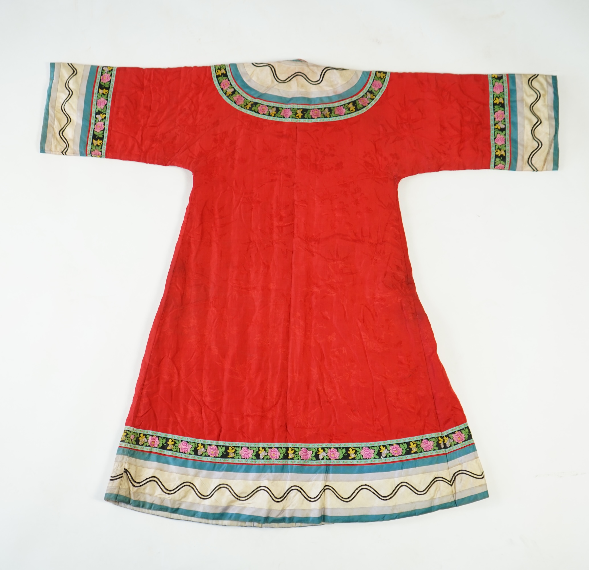 A late 19th century early 20th century Chinese red silk damask quilted Mandarin robe. Decorated with colourful rows braiding and ornate toggling. 116cm long. Condition - minor marks in places, may benefit from specialist